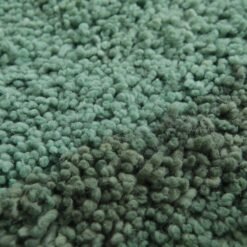 Macro close-up showing the soft, dense texture of natural lamb wool used in the Moroccan green and pistachio rug.