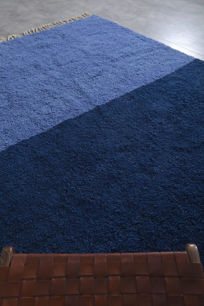 Detailed macro image of soft lamb wool texture in a handmade Moroccan rug featuring cobalt and light blue shades.