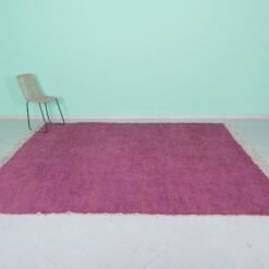 Top-down view of Moroccan plum rug showing solid wool surface and texture.
