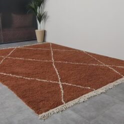 terracotta Moroccan wool rug featuring an ivory trellis design, showcasing the dense, plush wool texture and artisan hand-knotting.