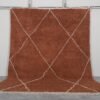 Handmade Moroccan rug with a warm terracotta background and soft ivory trellis pattern, woven by Berber artisans using 100% natural lamb wool in the classic Beni Ourain style.