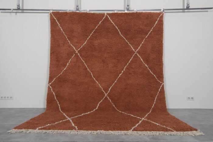 Handmade Moroccan rug with a warm terracotta background and soft ivory trellis pattern, woven by Berber artisans using 100% natural lamb wool in the classic Beni Ourain style.