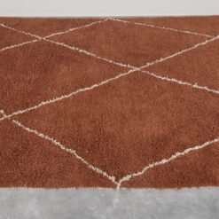 handmade terracotta Moroccan rug with ivory pattern, crafted from genuine lamb wool using traditional Berber techniques.
