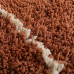 Detailed texture view showing thick lamb wool fibers and expert weaving in a warm terracotta Moroccan rug with ivory trellis lines.