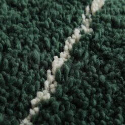 macro shot of the solid green Moroccan rug texture, capturing the softness and dense wool weave.
