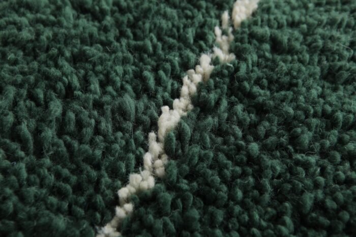 macro shot of the solid green Moroccan rug texture, capturing the softness and dense wool weave.