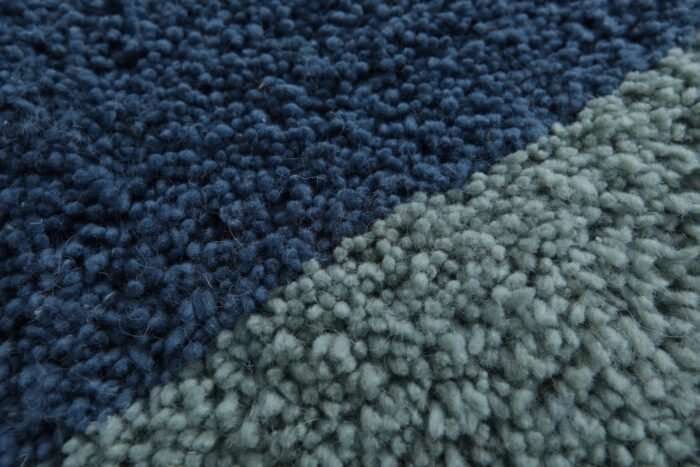 Zoomed-in view of dense lamb wool texture in Moroccan Beni Ourain rug with blue and pistachio hues, emphasizing softness and durability.