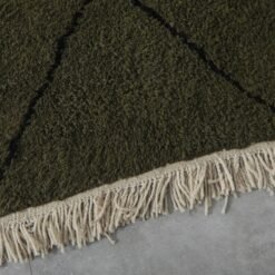 hand-knotted fringe on dark green and black Moroccan wool rug, showcasing authentic artisan finishing.