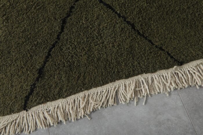 hand-knotted fringe on dark green and black Moroccan wool rug, showcasing authentic artisan finishing.