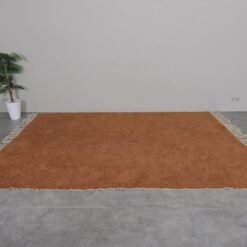 handwoven Moroccan rust wool rug, showcasing rich color and plush texture by Berber artisans.