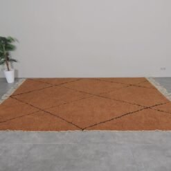 custom-sized rust and black Moroccan rug, emphasizing its plush wool pile and striking trellis pattern.