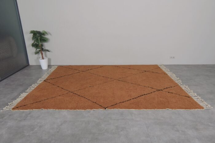 custom-sized rust and black Moroccan rug, emphasizing its plush wool pile and striking trellis pattern.