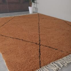handmade Berber rug in rust and black, highlighting detailed weaving and natural wool fibers in a traditional Beni Ourain pattern.