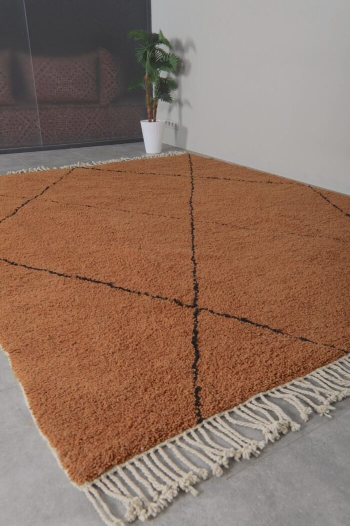 handmade Berber rug in rust and black, highlighting detailed weaving and natural wool fibers in a traditional Beni Ourain pattern.