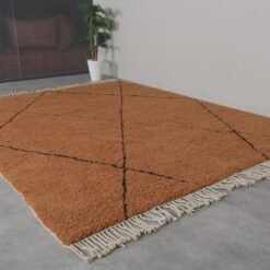 rust-colored Moroccan wool rug with bold black trellis design, showing thick plush texture and hand-knotted craftsmanship.