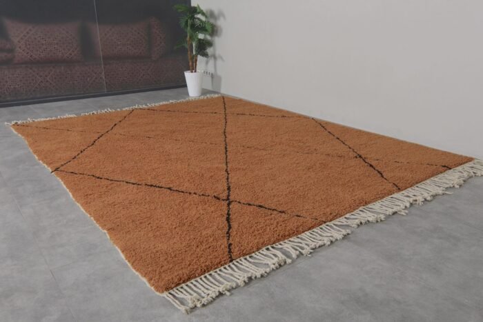 rust-colored Moroccan wool rug with bold black trellis design, showing thick plush texture and hand-knotted craftsmanship.