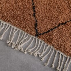 hand-knotted fringe on rust and black Moroccan wool rug, showcasing authentic artisan finishing techniques.