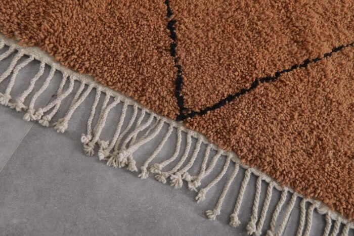 hand-knotted fringe on rust and black Moroccan wool rug, showcasing authentic artisan finishing techniques.