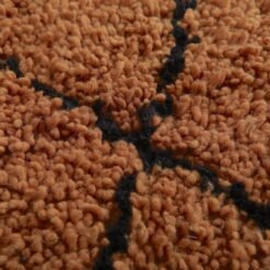 Macro shot highlighting dense lamb wool fibers and rich texture of rust and black handmade Moroccan rug.