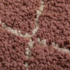 Macro shot of plush lamb wool texture in a handmade chestnut Moroccan rug with ivory trellis, showing the warmth and softness of the material.