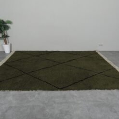green Moroccan wool rug featuring black geometric trellis design, showing thick plush texture and expert hand-knotting.