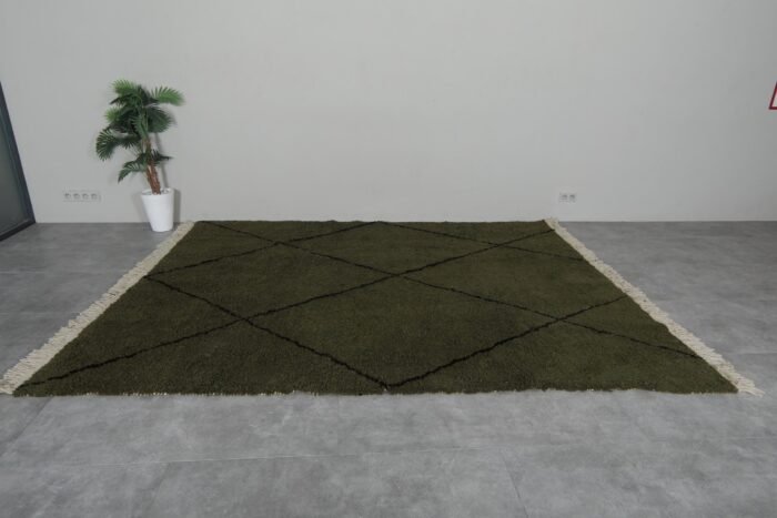 green Moroccan wool rug featuring black geometric trellis design, showing thick plush texture and expert hand-knotting.