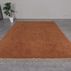 Moroccan rust-colored rug, highlighting dense wool fibers and artisanal craftsmanship.