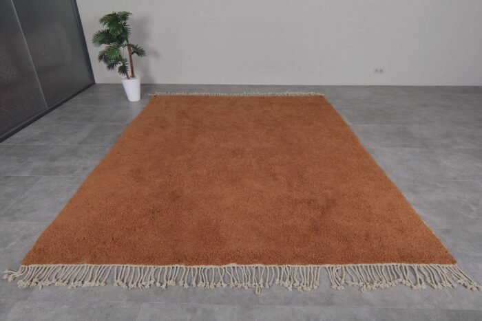 Moroccan rust-colored rug, highlighting dense wool fibers and artisanal craftsmanship.