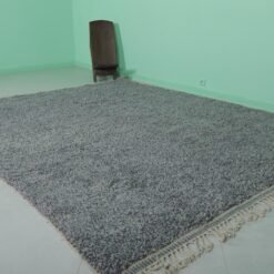 handmade Moroccan gray wool Beni Ourain rug showing the thick, plush wool texture and authentic tribal geometric designs, made by Berber women artisans in the Atlas Mountains