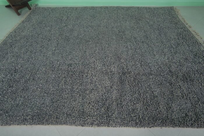Overhead view of an authentic handmade Moroccan gray wool rug with traditional Beni Ourain tribal designs, emphasizing the thick wool pile and expert hand-knotting by Berber artisans.