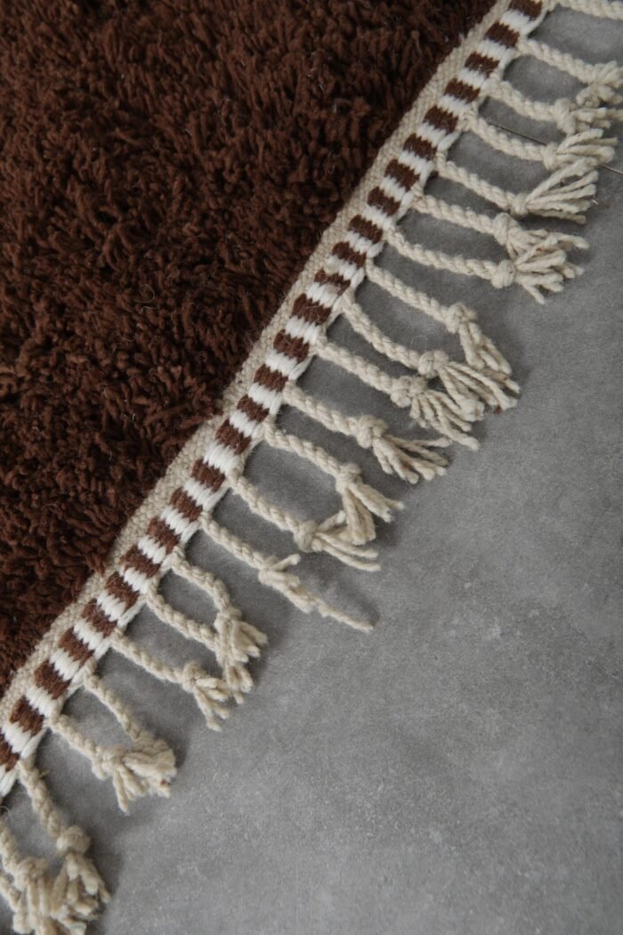 fringes on Moroccan wool rug in brown and ivory, highlighting handmade finish and traditional Berber weaving.