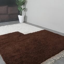 Folded edge of ivory and brown Moroccan rug, showing density and premium handmade wool structure.