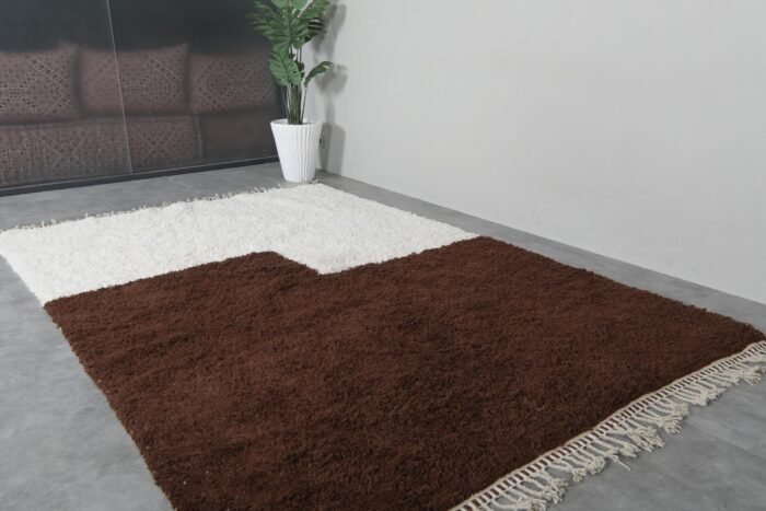 Folded edge of ivory and brown Moroccan rug, showing density and premium handmade wool structure.