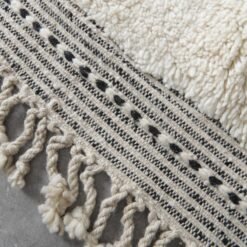 hand-knotted fringe on ivory and black trellis Moroccan rug, showing authentic artisan finishing techniques.