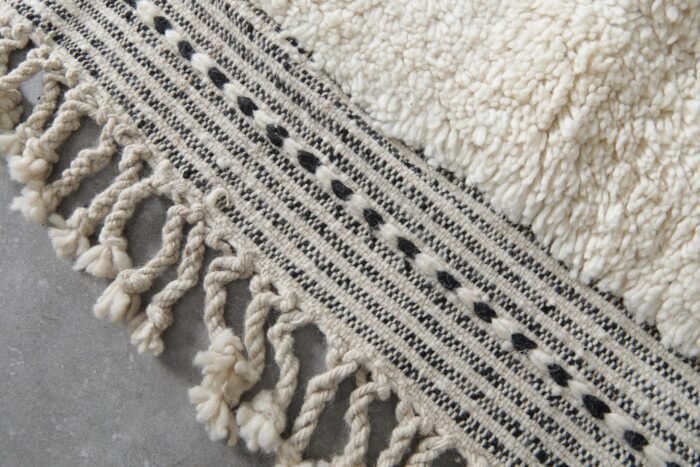 hand-knotted fringe on ivory and black trellis Moroccan rug, showing authentic artisan finishing techniques.