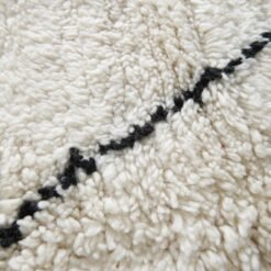 Macro shot highlighting dense lamb wool fibers and rich texture of ivory and black Moroccan hand-knotted rug.