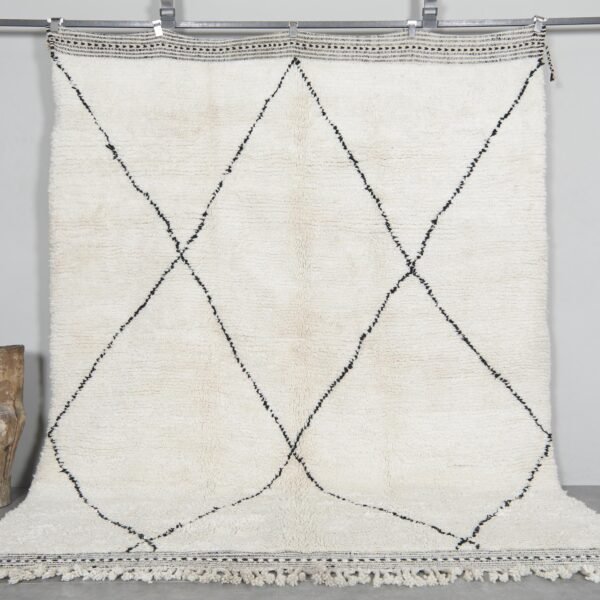 Hand-knotted Moroccan rug featuring an ivory base with bold black trellis pattern, crafted from 100% natural lamb wool by skilled Berber artisans in Morocco.