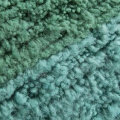 Zoomed-in wool texture showing dense, high-quality lamb wool in forest green and soft aqua shades.