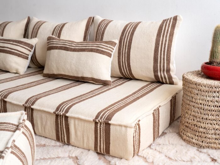 Side view of long Moroccan floor cushion in cream with brown stripes on wooden floor