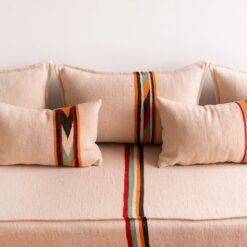 Accent pillow with orange and black embroidery detail on cream wool
