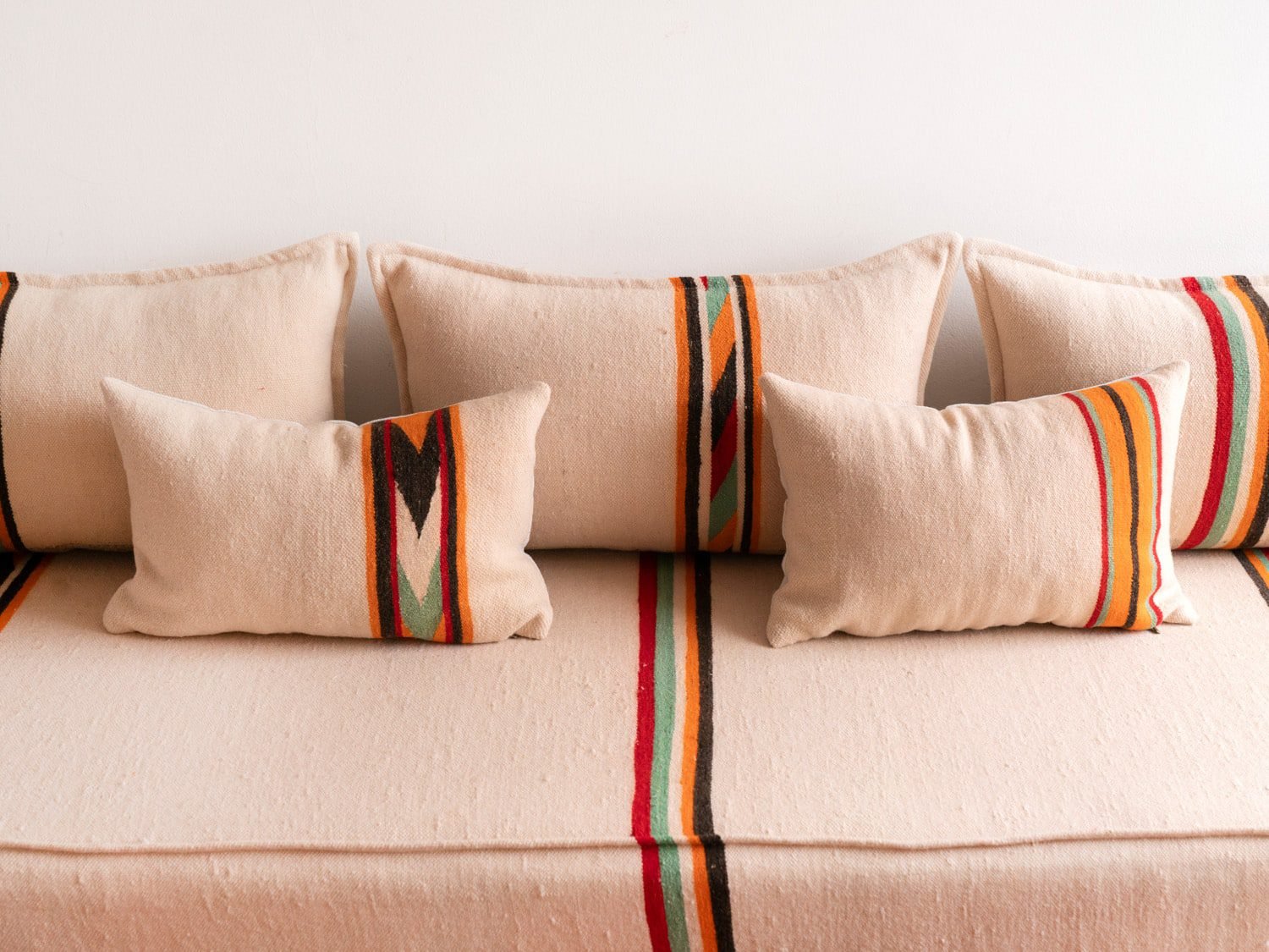 Accent pillow with orange and black embroidery detail on cream wool