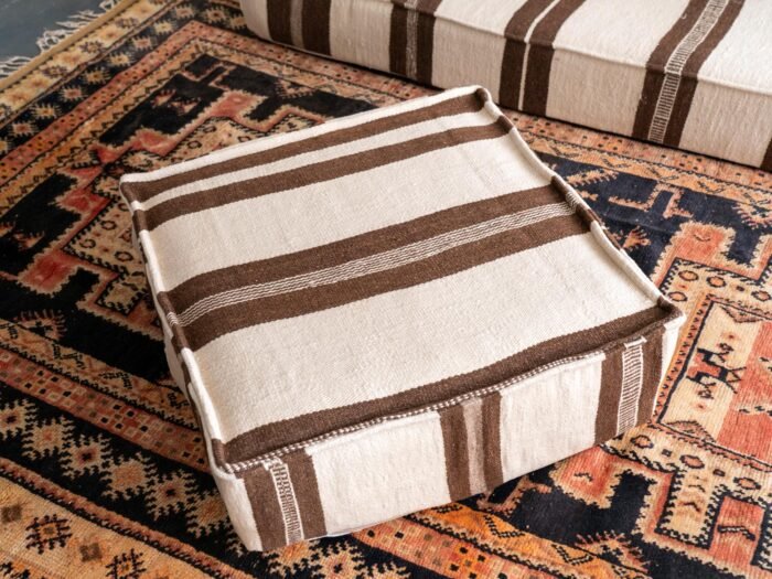Artisan hand-finishing ivory wool cushion with brown embroidery