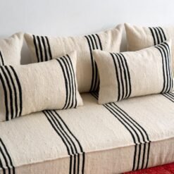 Artisan hand-embroidering black lines on cream wool fabric