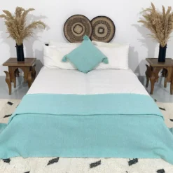 Moroccan turquoise pompom throw styled on a cozy bed