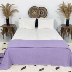 Purple pompom throw styled in a boho-inspired bedroom setup