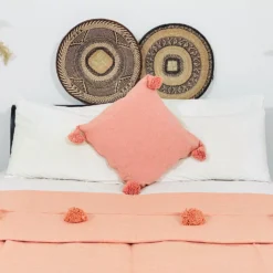 Salmon Moroccan cotton blanket with pompoms styled on a modern sofa