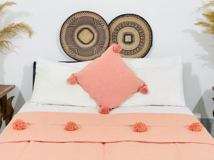 Salmon Moroccan cotton blanket with pompoms styled on a modern sofa
