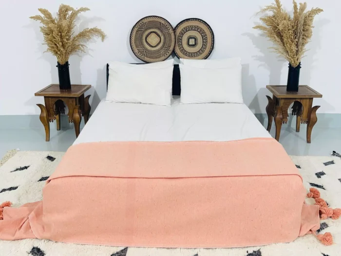 Moroccan pompom throw styled on a boho-style bed in a cozy bedroom