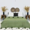 Handmade Moroccan pompom blanket in olive green, styled on a modern bed