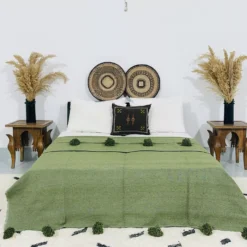 Handmade Moroccan pompom blanket in olive green, styled on a modern bed